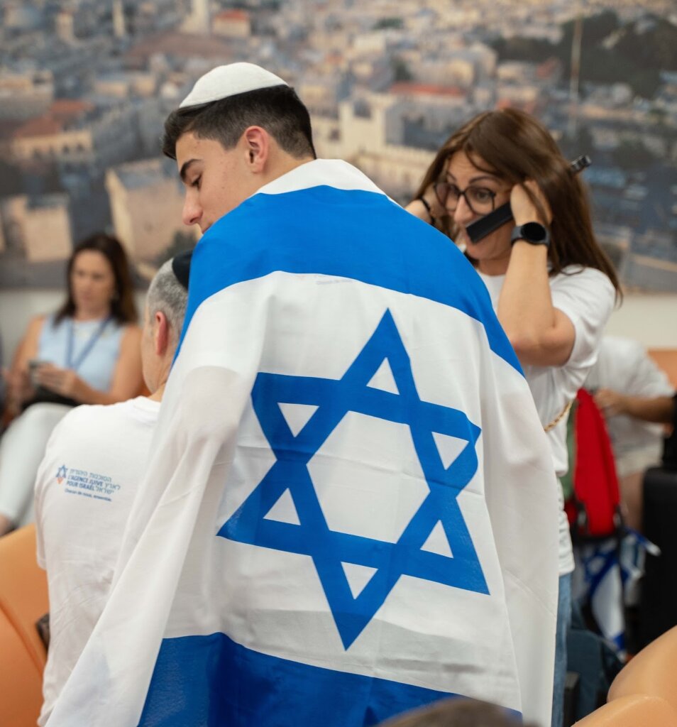 A youth adorns the Israeli flag upon making Aliyah from France (JAFI)